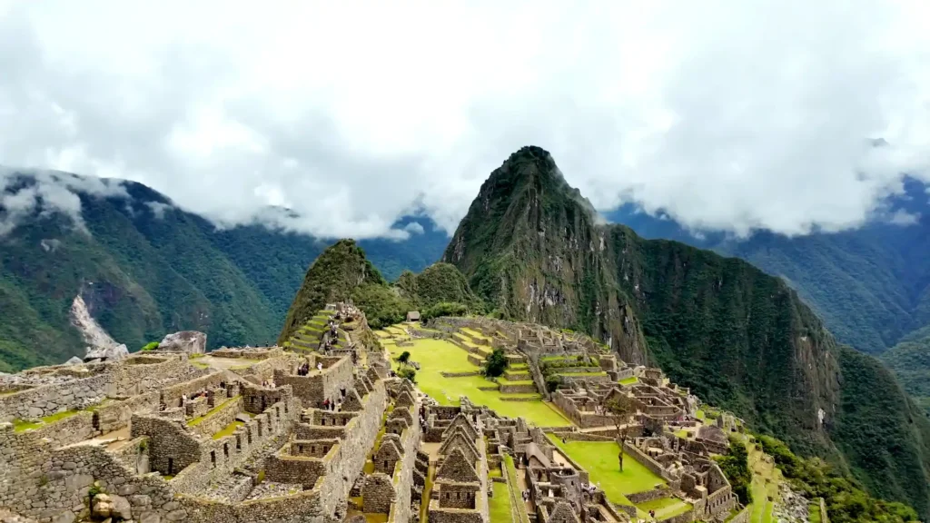 Vista panorámica de Machu Picchu rodeado de montañas y nubes, uno de los principales lugares turísticos de la sierra peruana.