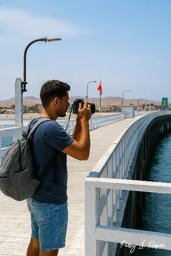 Turista capturando una fotografía desde el muelle de Cerro Azul, un ícono del turismo en Cañete